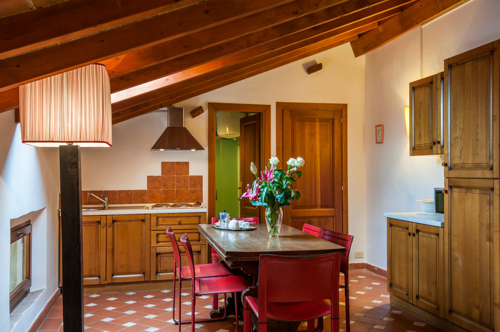 На фото: кухня-столовая в стиле кантри с белыми стенами, полом из терракотовой плитки и красным полом