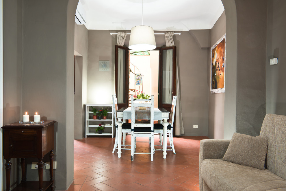 Cette photo montre une petite salle à manger ouverte sur le salon moderne avec un mur gris, tomettes au sol et un sol orange.