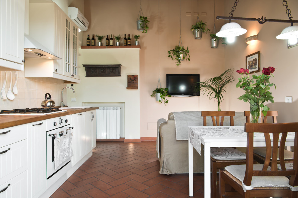 Exemple d'une petite salle à manger ouverte sur la cuisine tendance avec un mur rose, tomettes au sol et un sol orange.