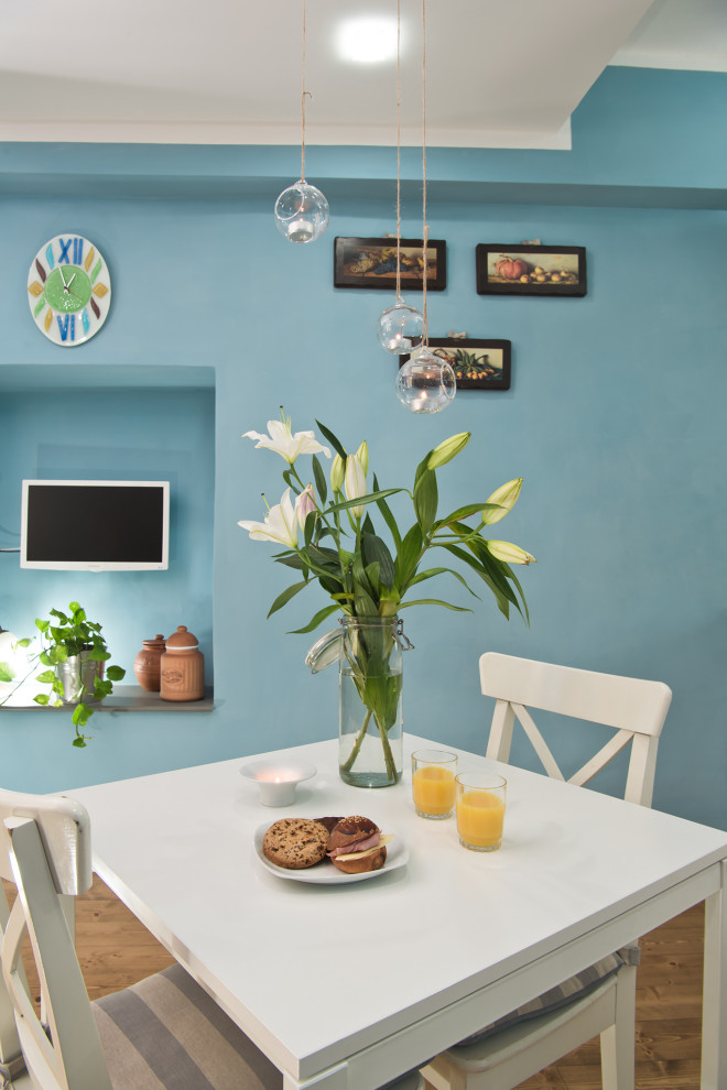 Immagine di una piccola sala da pranzo aperta verso la cucina minimal con pareti blu, parquet chiaro e pavimento marrone