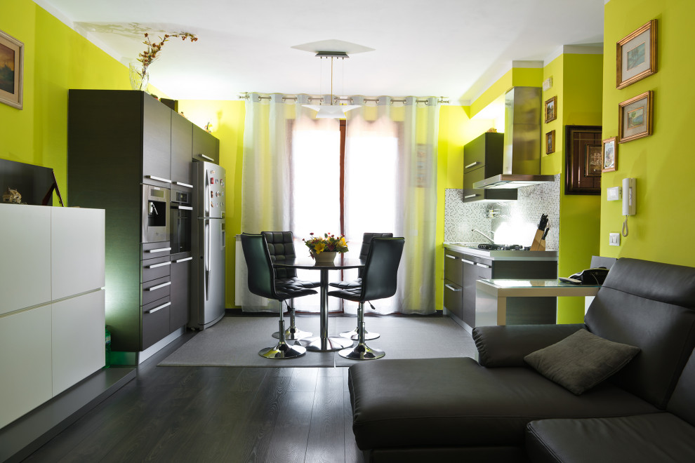 Cette photo montre une salle à manger ouverte sur le salon tendance de taille moyenne avec un mur vert, parquet foncé et un sol marron.