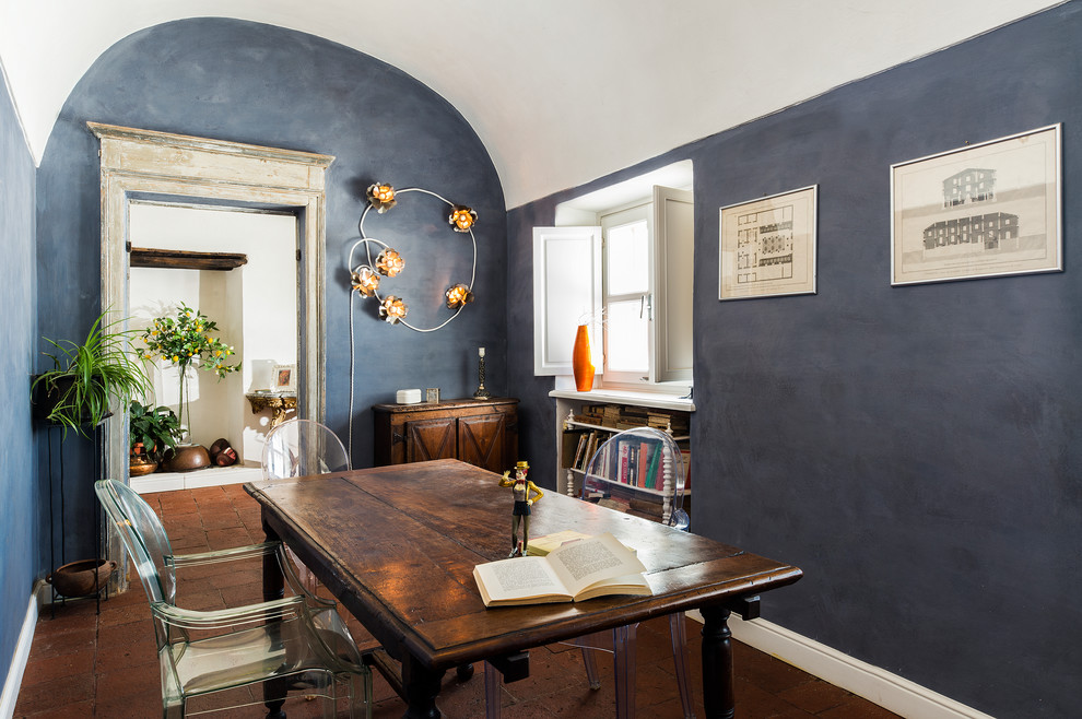 Aménagement d'une salle à manger éclectique fermée avec un mur bleu, tomettes au sol, un sol rouge et aucune cheminée.