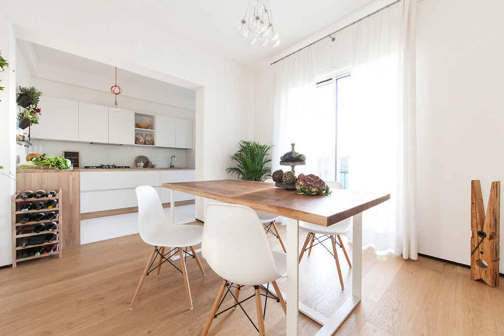 This is an example of a contemporary kitchen/dining room in Venice with white walls and light hardwood flooring.