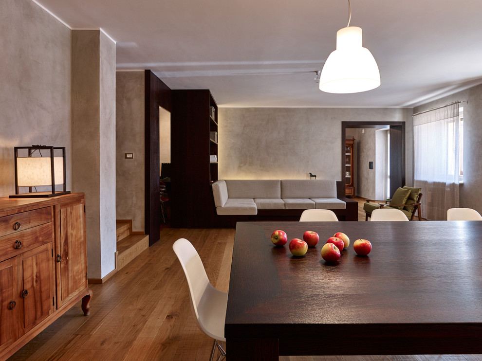 Immagine di una sala da pranzo aperta verso il soggiorno contemporanea con pareti grigie e pavimento in legno massello medio