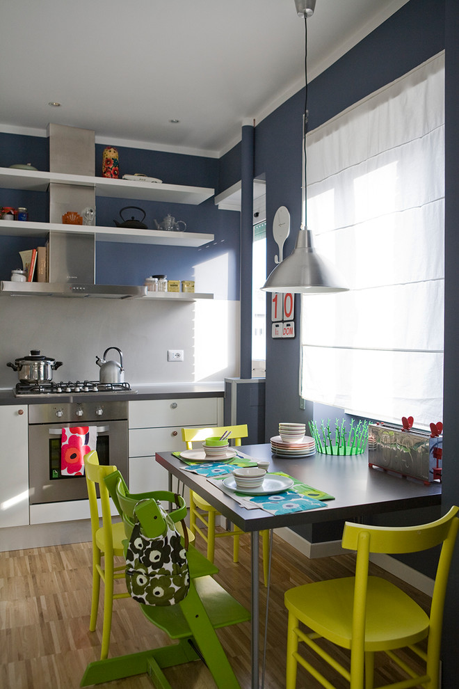 Idée de décoration pour une salle à manger ouverte sur la cuisine design avec un mur bleu, parquet clair et un sol beige.