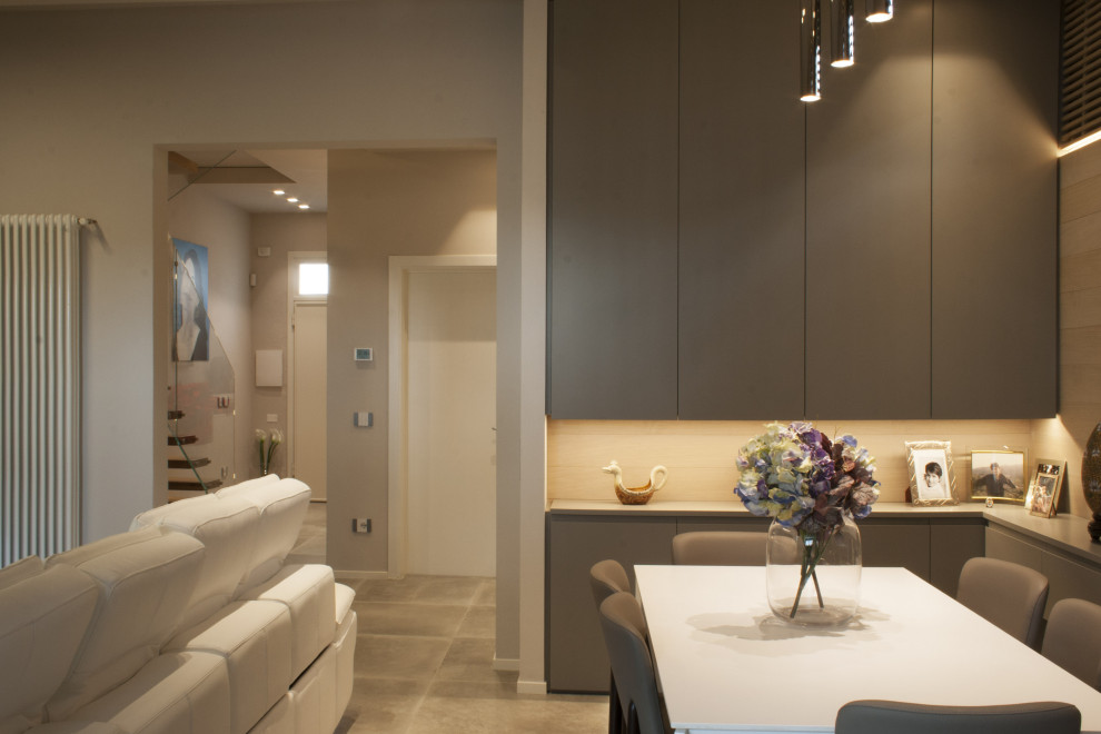 На фото: маленькая гостиная-столовая в стиле модернизм с серыми стенами, полом из керамогранита и серым полом для на участке и в саду