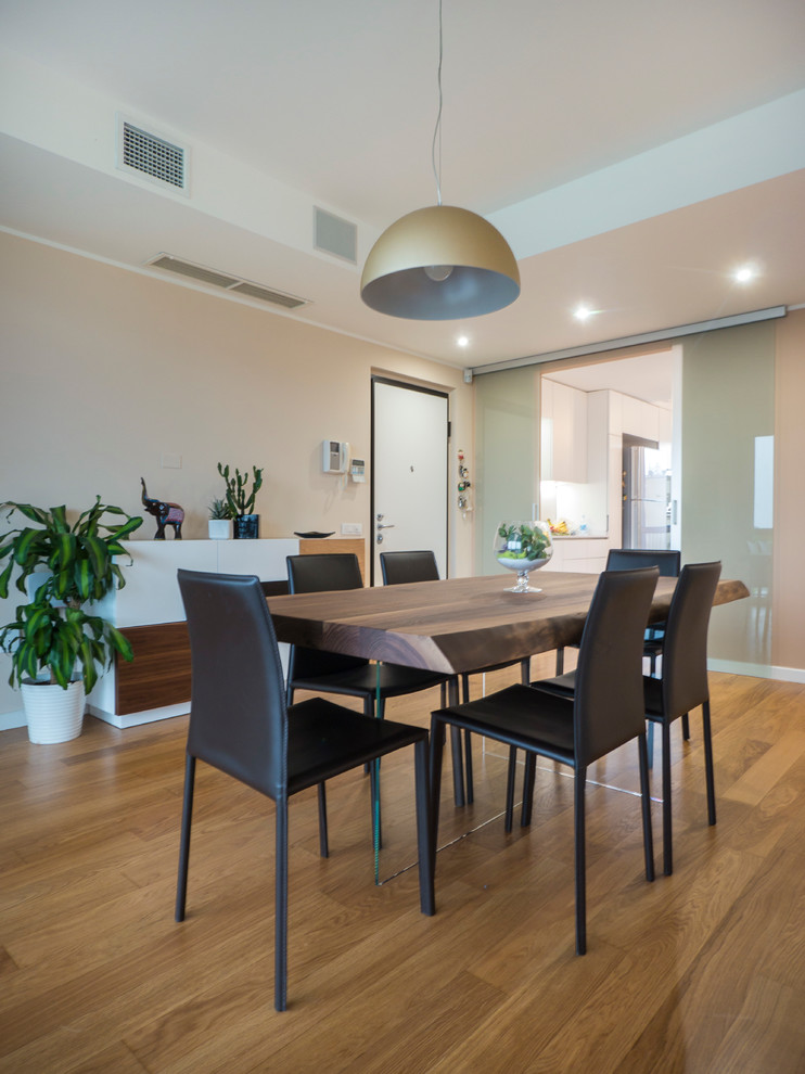 This is an example of a medium sized contemporary open plan dining room in Milan with light hardwood flooring and beige walls.