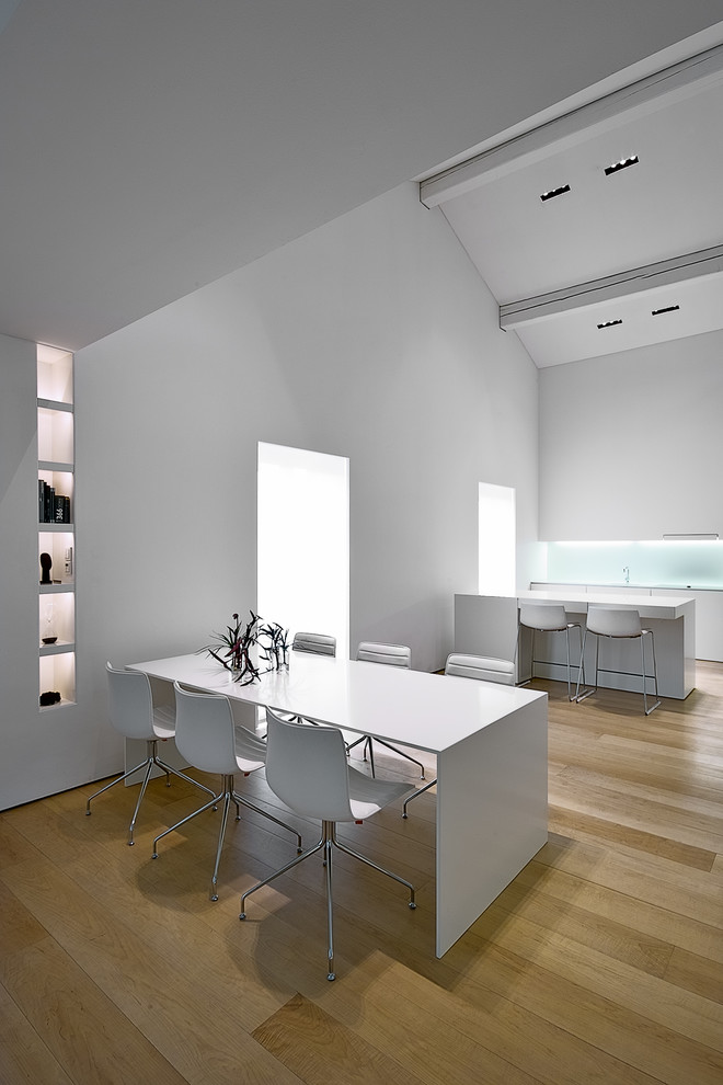 Réalisation d'une salle à manger ouverte sur la cuisine minimaliste avec parquet clair.