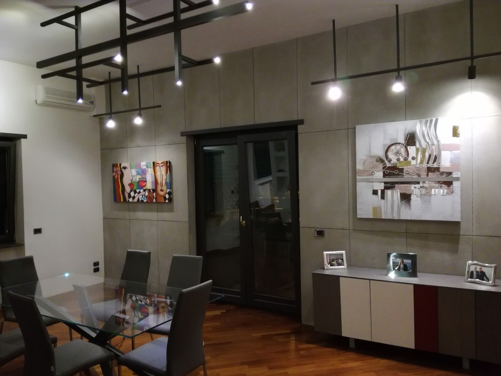 Foto di una grande sala da pranzo aperta verso il soggiorno industriale con pareti grigie, parquet scuro e pavimento marrone