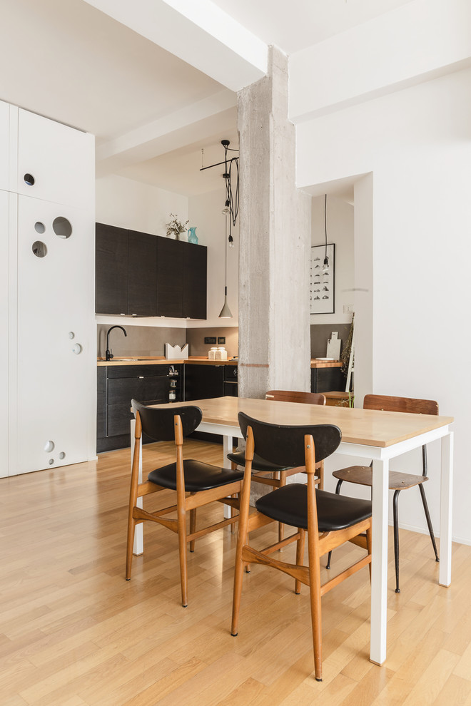 Immagine di una piccola sala da pranzo aperta verso la cucina design con pareti bianche, parquet chiaro e nessun camino