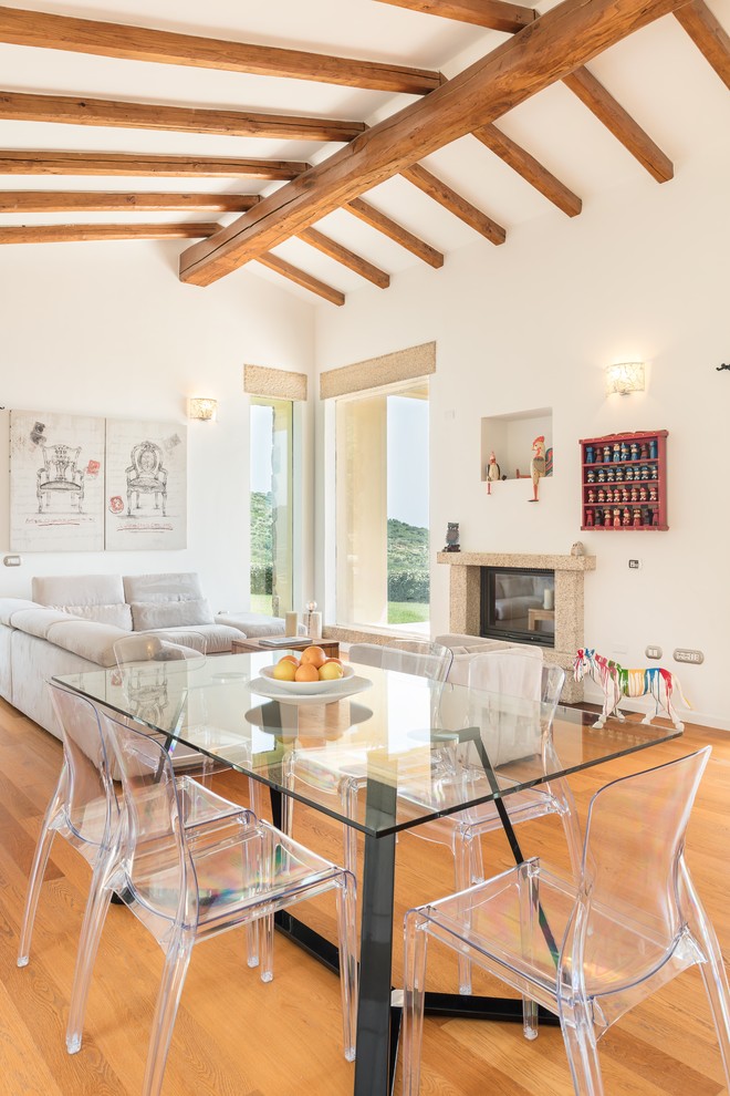 Ispirazione per una sala da pranzo aperta verso il soggiorno mediterranea con pareti bianche, pavimento in legno massello medio, camino classico e pavimento beige