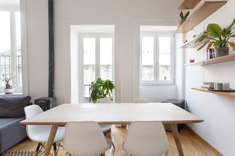 Foto di una sala da pranzo aperta verso il soggiorno scandinava con pareti bianche, pavimento in legno massello medio, stufa a legna e pavimento marrone