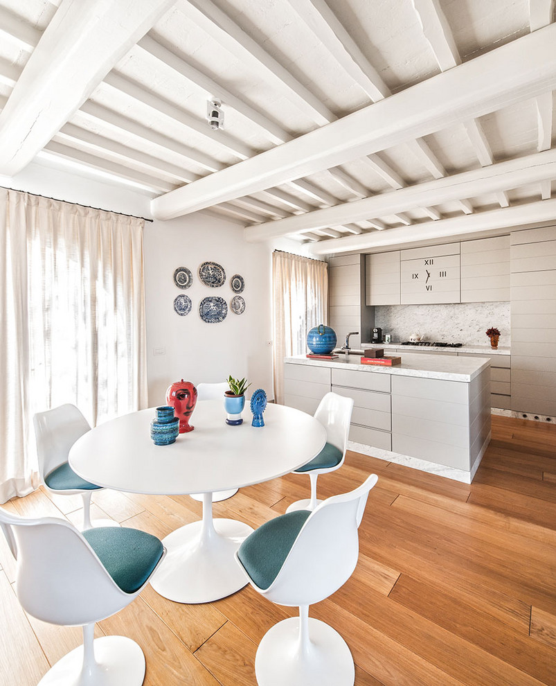 Immagine di una sala da pranzo aperta verso la cucina mediterranea con pavimento in legno massello medio e pareti bianche