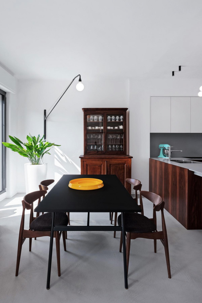 Foto di una grande sala da pranzo aperta verso la cucina contemporanea con pareti bianche, pavimento in cemento e pavimento grigio