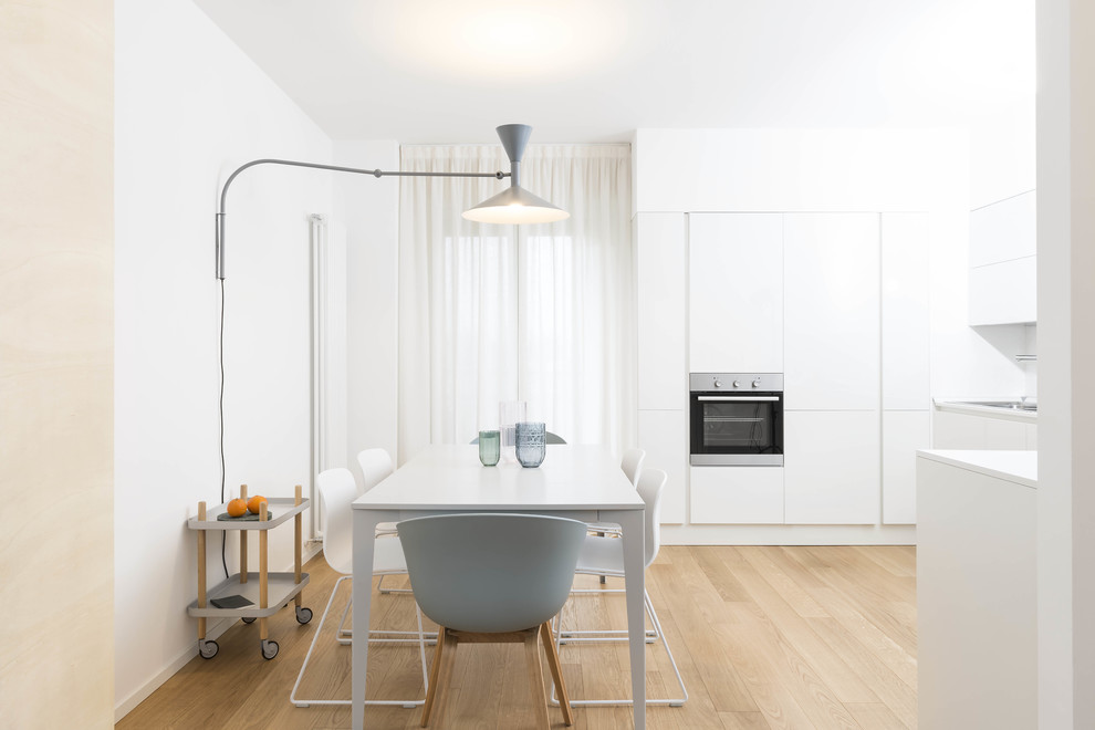 Ispirazione per una sala da pranzo aperta verso la cucina nordica con pareti bianche, parquet chiaro e pavimento beige