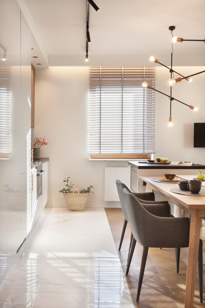 Ispirazione per una sala da pranzo aperta verso la cucina moderna di medie dimensioni con pareti bianche, pavimento in gres porcellanato e pavimento bianco
