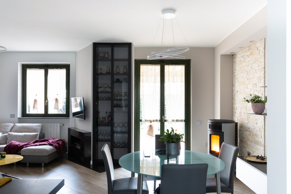 Foto di una sala da pranzo aperta verso il soggiorno contemporanea con pareti beige, pavimento in gres porcellanato e pareti in mattoni