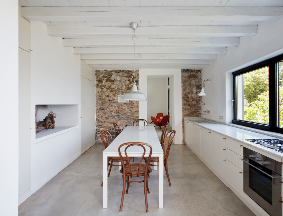 На фото: большая кухня-столовая в современном стиле с белыми стенами и бетонным полом