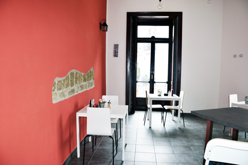 Idee per una sala da pranzo aperta verso la cucina moderna di medie dimensioni con pareti rosse, pavimento in gres porcellanato e pavimento nero