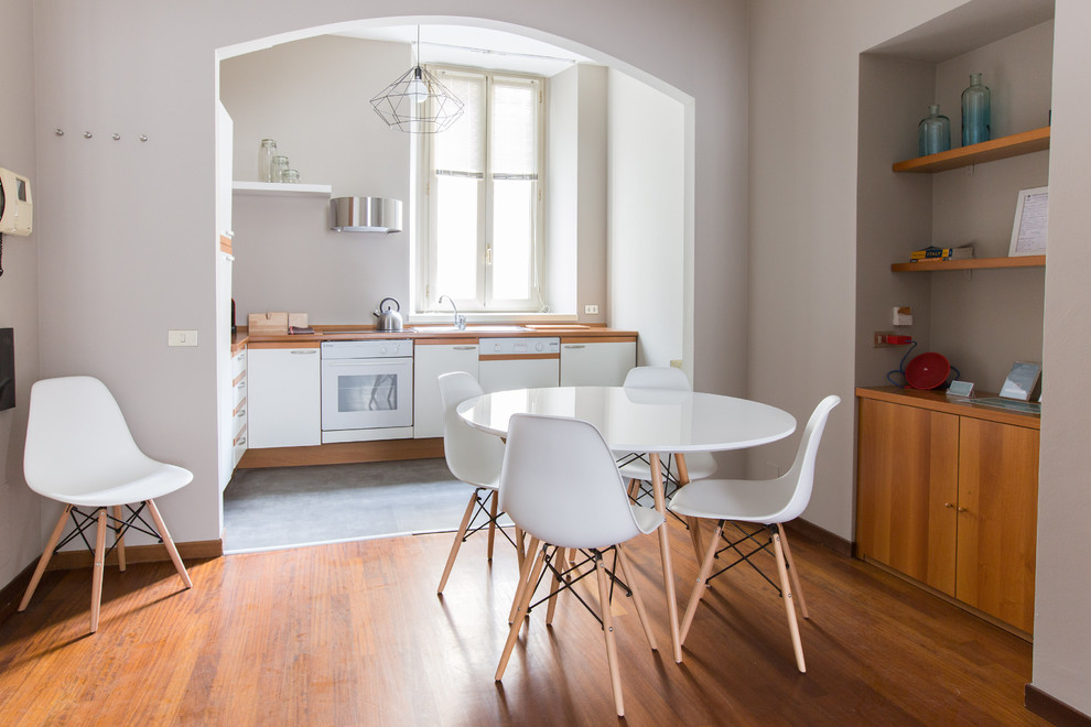 Kleines Nordisches Esszimmer ohne Kamin mit braunem Boden, grauer Wandfarbe und braunem Holzboden in Mailand