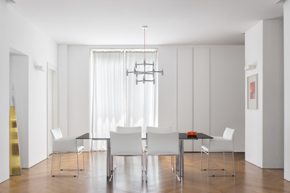 Photo of a medium sized contemporary enclosed dining room in Milan with white walls and medium hardwood flooring.