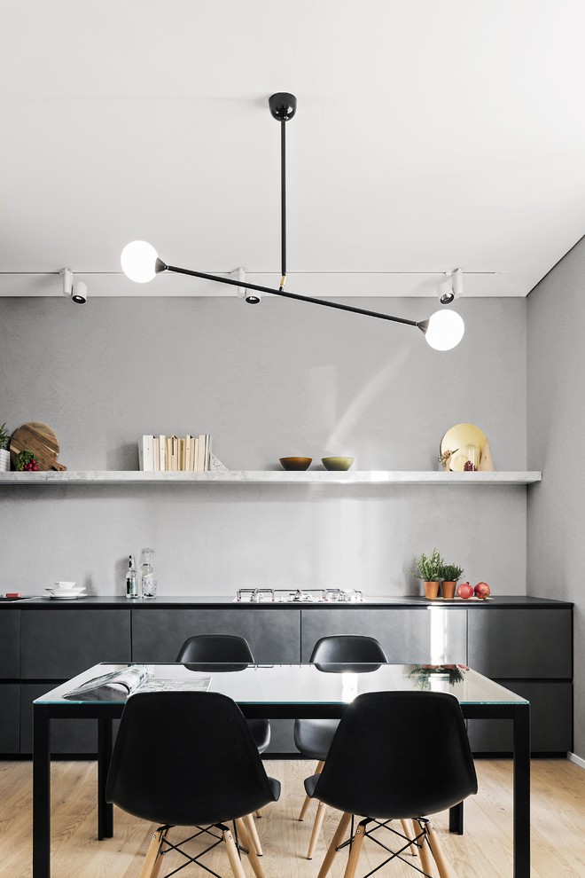 Immagine di una sala da pranzo aperta verso la cucina minimal di medie dimensioni con pareti grigie e parquet chiaro
