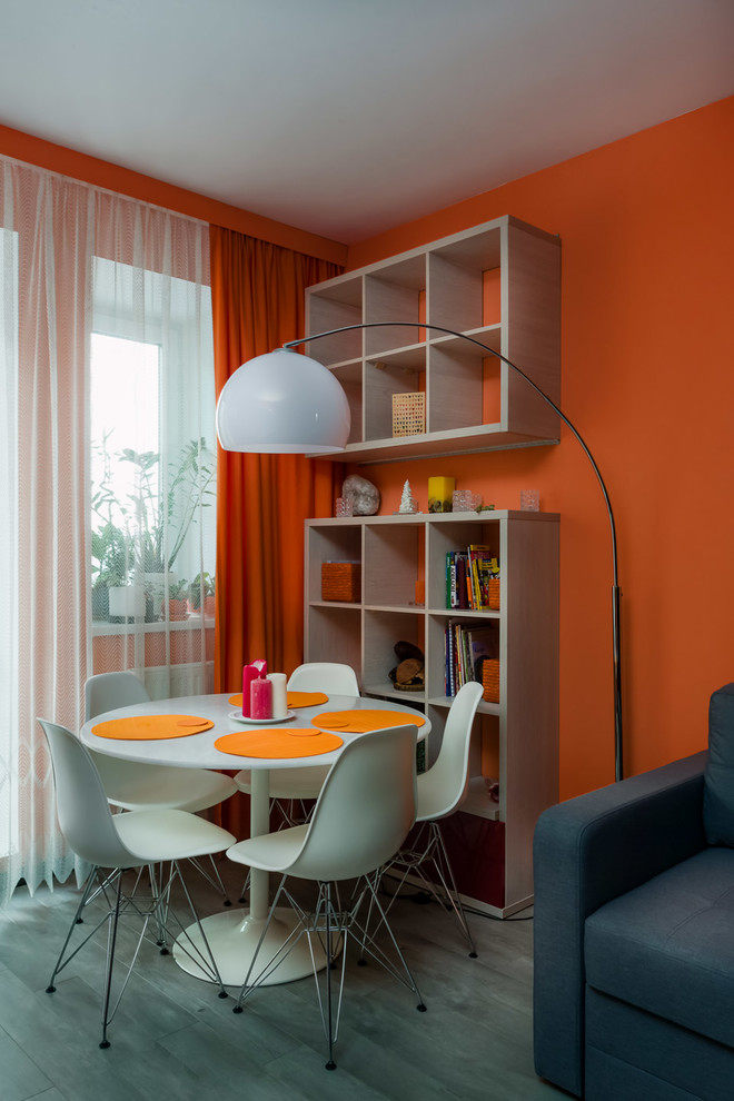 Idee per una piccola sala da pranzo aperta verso il soggiorno minimalista con pareti arancioni, pavimento in laminato e pavimento grigio