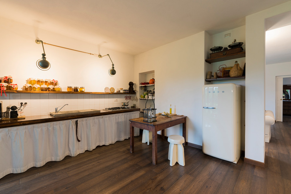Immagine di una grande sala da pranzo aperta verso la cucina stile shabby con pareti bianche e pavimento in legno massello medio