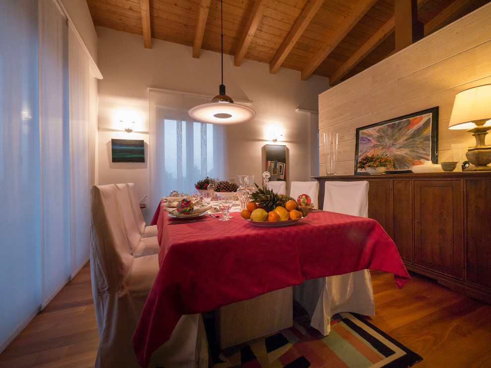 Cette photo montre une salle à manger ouverte sur le salon éclectique de taille moyenne avec un mur blanc, un sol en bois brun et aucune cheminée.