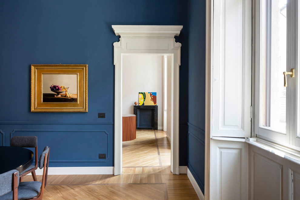 Aménagement d'une grande salle à manger ouverte sur la cuisine contemporaine avec un mur bleu, parquet clair, une cheminée standard, un manteau de cheminée en pierre et un sol marron.