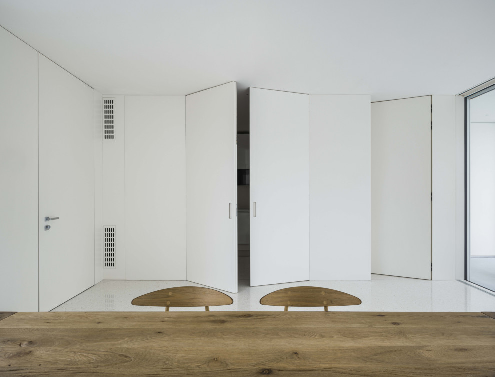 Foto di una grande sala da pranzo aperta verso il soggiorno contemporanea con pareti bianche, pavimento bianco e boiserie
