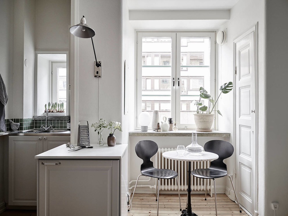 Ejemplo de comedor de cocina escandinavo pequeño sin chimenea con paredes blancas y suelo de madera clara