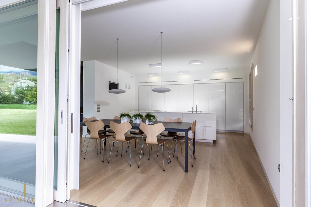 Immagine di una sala da pranzo minimalista con parquet chiaro