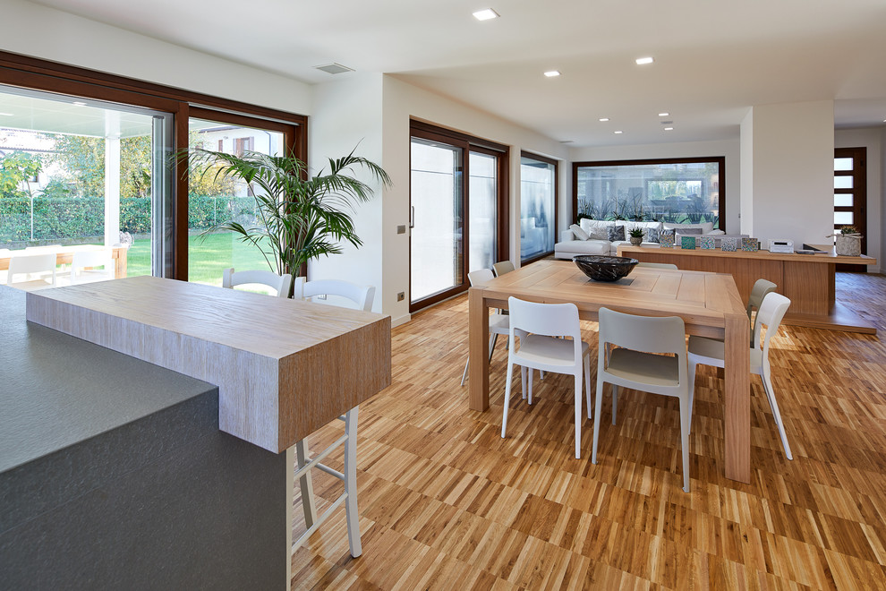 Example of a mid-sized minimalist light wood floor and brown floor kitchen/dining room combo design in Other with white walls