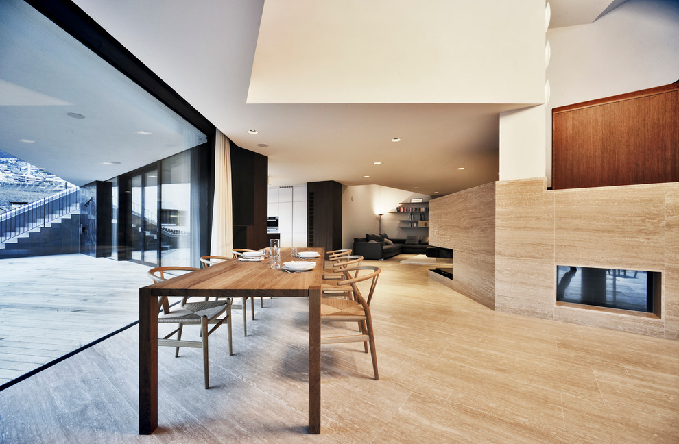 Imagen de comedor moderno abierto con paredes blancas, suelo de madera clara, chimenea lineal y marco de chimenea de piedra