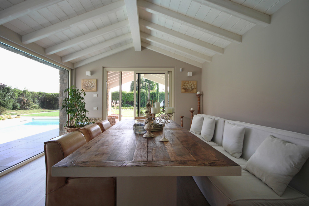 Große Landhausstil Wohnküche mit braunem Holzboden, braunem Boden, freigelegten Dachbalken und grauer Wandfarbe in Mailand