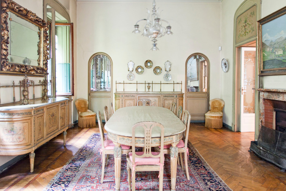 Geschlossenes, Großes Klassisches Esszimmer mit Kamin, Kaminumrandung aus Backstein und braunem Holzboden in Mailand