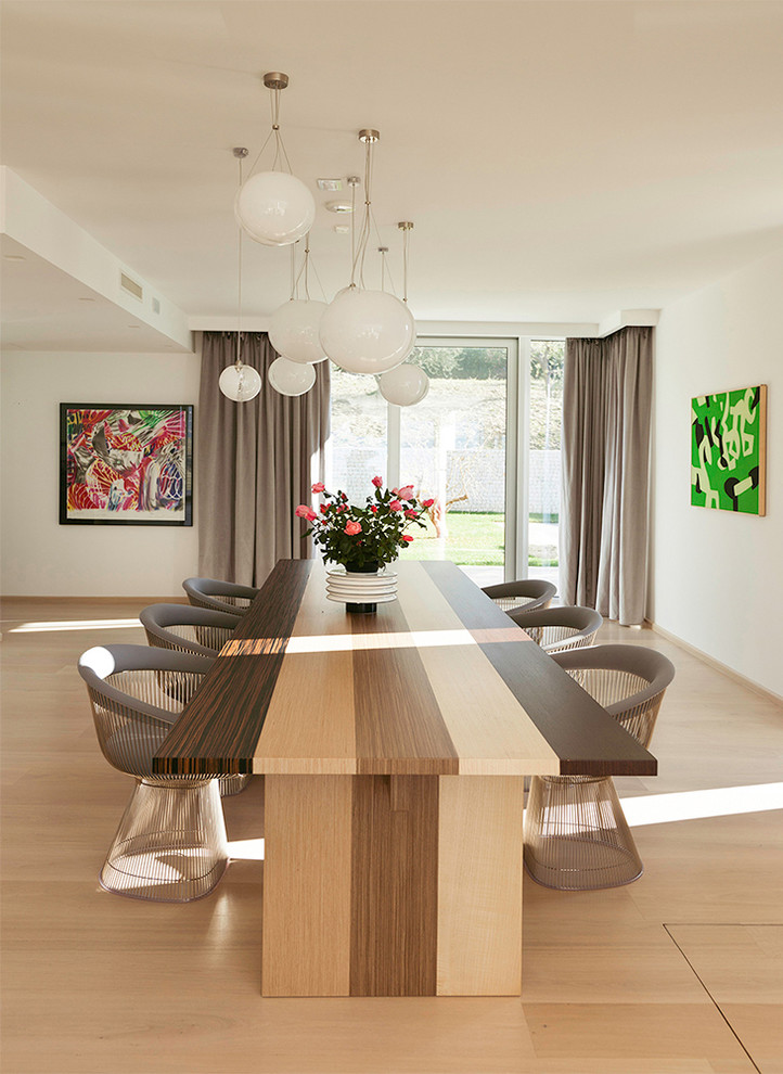 Cette image montre une salle à manger ouverte sur le salon design avec un mur blanc, parquet clair et un sol beige.