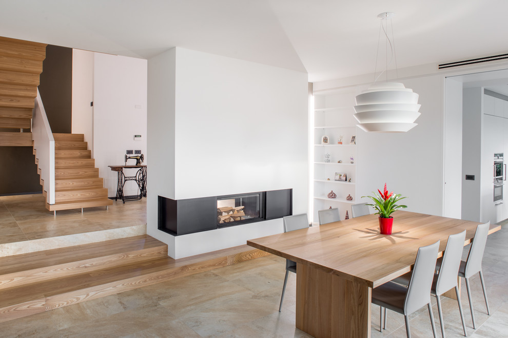 Cette image montre une salle à manger ouverte sur le salon design avec un mur blanc, une cheminée double-face et un sol beige.