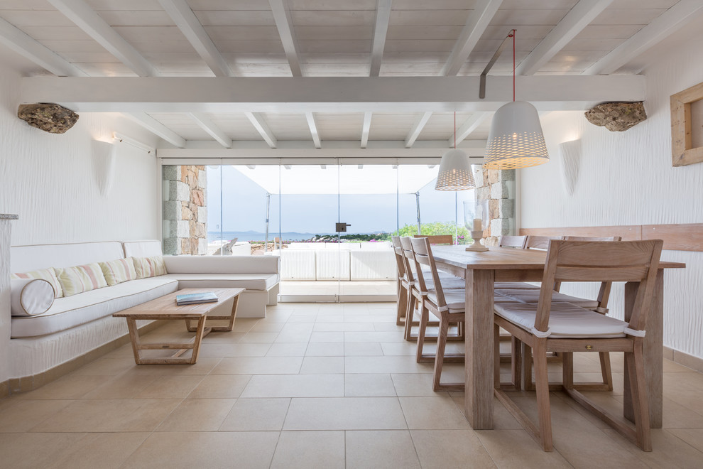Foto di una sala da pranzo aperta verso il soggiorno mediterranea con pareti bianche e pavimento beige