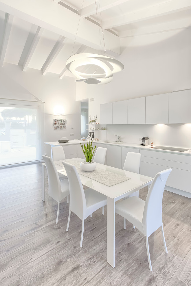 Ispirazione per una sala da pranzo aperta verso la cucina minimal di medie dimensioni con pareti bianche, pavimento in laminato e pavimento grigio