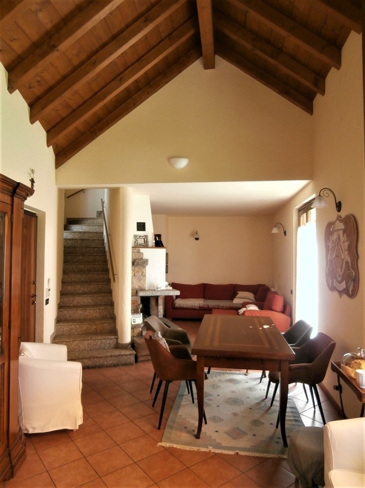 Exemple d'une salle à manger chic avec un mur blanc, un sol en carrelage de porcelaine, une cheminée standard, un manteau de cheminée en pierre et un sol rouge.