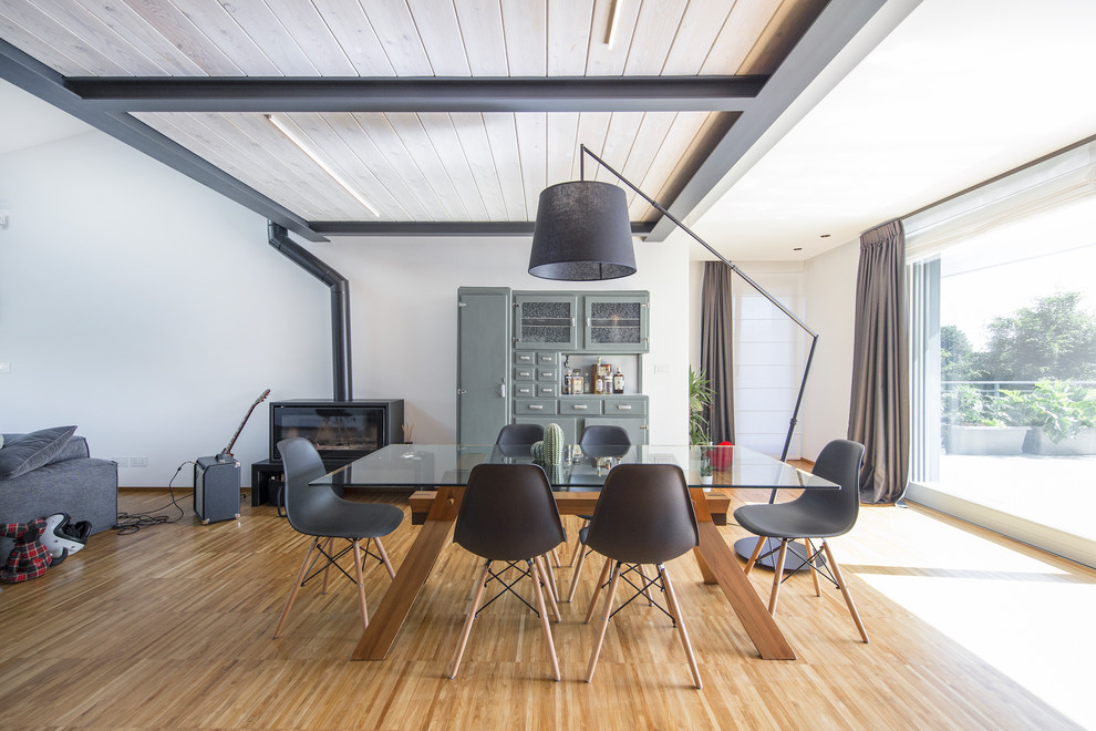 Offenes Modernes Esszimmer mit weißer Wandfarbe, hellem Holzboden, Kaminofen und beigem Boden in Turin