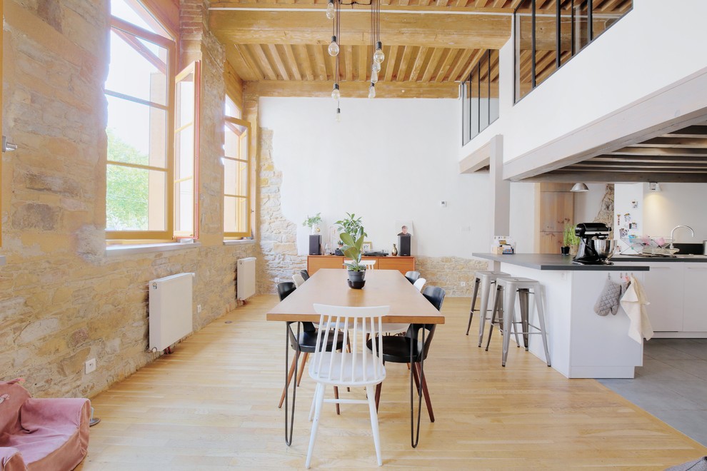 Imagen de comedor industrial abierto sin chimenea con paredes beige, suelo de madera clara y suelo beige