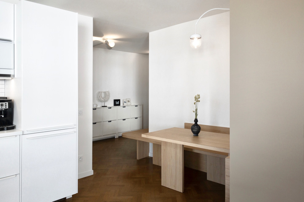 Cette image montre une salle à manger ouverte sur le salon design de taille moyenne avec un mur blanc et un sol en bois brun.