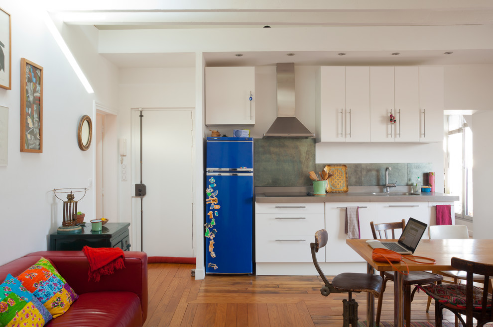 Réalisation d'une salle à manger ouverte sur la cuisine design de taille moyenne avec un mur blanc et un sol en bois brun.