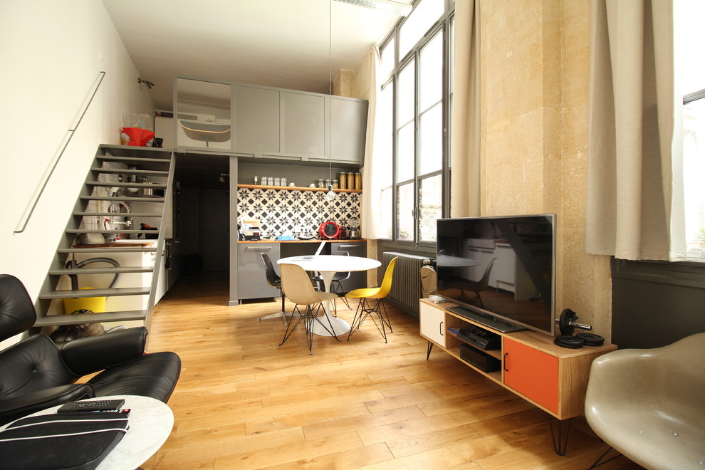 Great room - small industrial medium tone wood floor great room idea in Paris with white walls and no fireplace