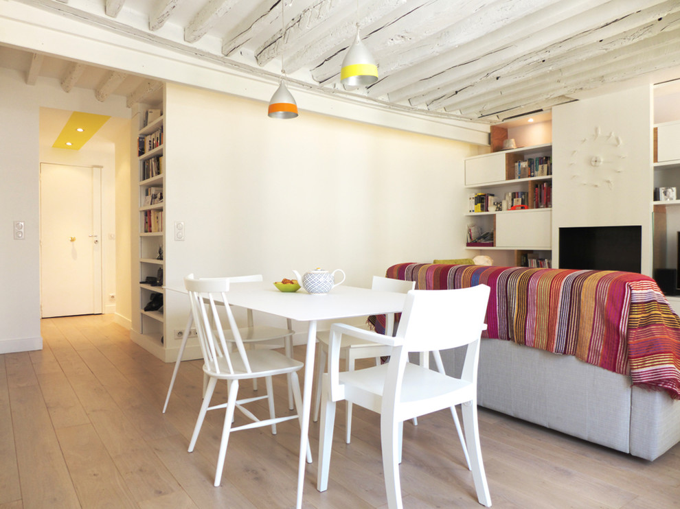 Cette image montre une salle à manger ouverte sur le salon design de taille moyenne avec un mur blanc, parquet clair et cheminée suspendue.