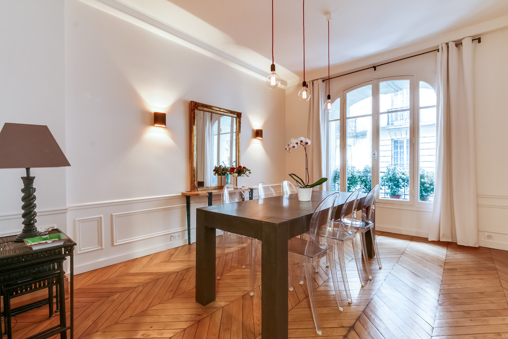 Photo of a large traditional enclosed dining room in Paris with white walls, light hardwood flooring, no fireplace and feature lighting.