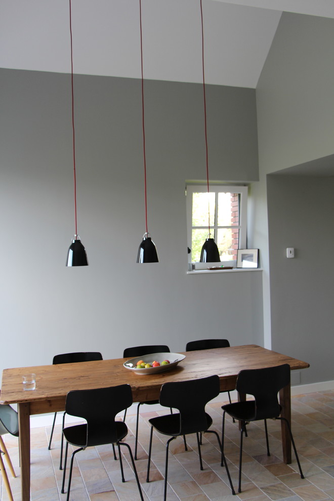 Foto di una sala da pranzo aperta verso il soggiorno minimalista di medie dimensioni con pareti grigie, pavimento in terracotta e camino classico